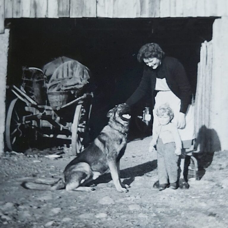Großmutter mit Kind und Schäferhund vor Werkstatt